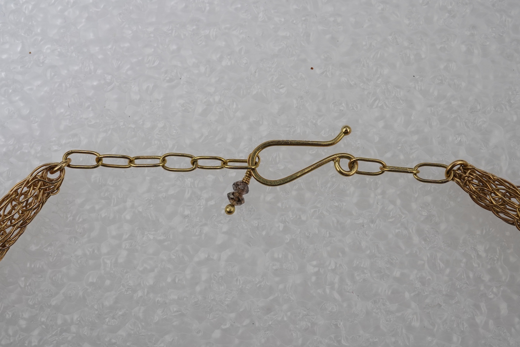 An 18ct gold and diamond necklace, composed of a woven tube of 18ct gold wire links, three sections threaded with brown diamond beads, length approximately 45cm, British hallmarks, sponsor's mark TJH, gross weight approx